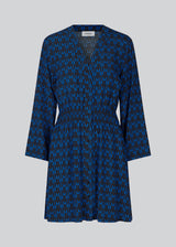 Short printed dress in the color: Graphic Heart Bright Ocean. BorysMD print dress has a v neckline med button closure in the front and smock detail in the waist. The style has long wide sleeves.
