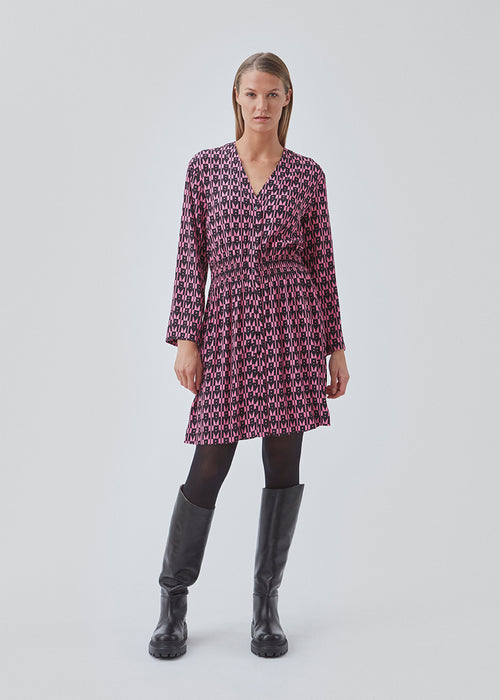 Short printed dress in the color: Graphic Heart Cosmos Pink. BorysMD print dress has a v neckline med button closure in the front and smock detail in the waist. The style has long wide sleeves.