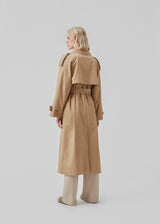 Double breasted beige trench coat made from a woven cotton. BrodaMD solid coat features a collar, storm flap, and a tie-belt at the waist. The fit is relaxed.