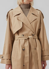 Double breasted beige trench coat made from a woven cotton. BrodaMD solid coat features a collar, storm flap, and a tie-belt at the waist. The fit is relaxed.