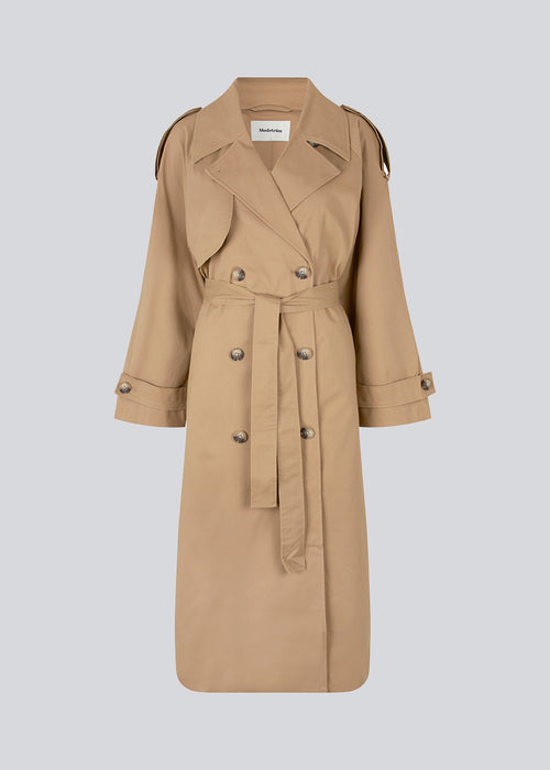 Double breasted beige trench coat made from a woven cotton. BrodaMD solid coat features a collar, storm flap, and a tie-belt at the waist. The fit is relaxed.  The model is 177 cm and wears a size S/36.