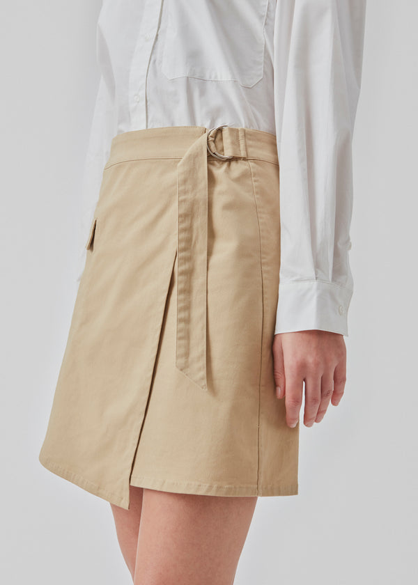 Short skirt with cargo details in a woven cotton twill. CalaMD skirt has a wrap detail with a D-ring, asymmetrical details, and patch pockets. The model is 177 cm and wears a size S/36.  Shop matching jacket: CalaMD jacket