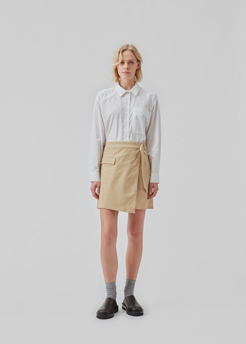 Short skirt with cargo details in a woven cotton twill. CalaMD skirt has a wrap detail with a D-ring, asymmetrical details, and patch pockets. The model is 177 cm and wears a size S/36.  Shop matching jacket: CalaMD jacket