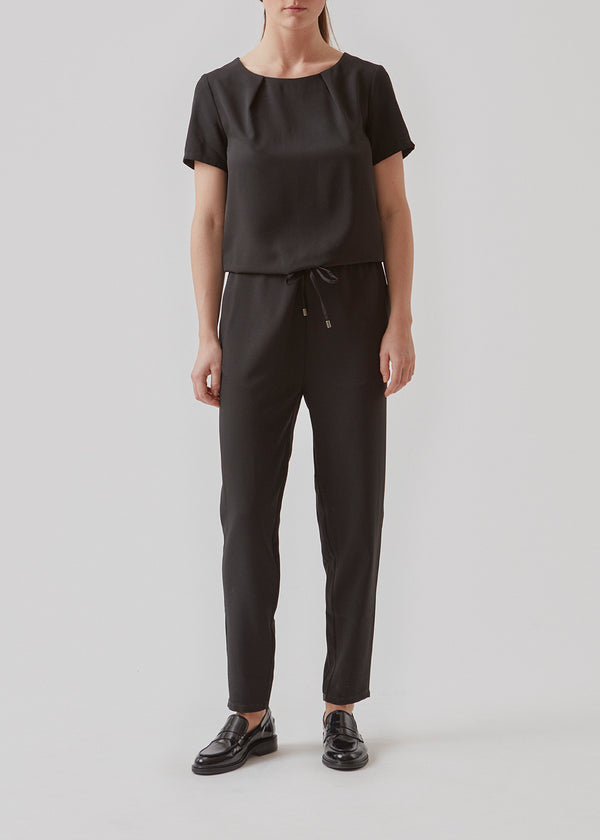 Classic jumpsuit with short sleeves. Campell jumpsuit has a tie string which highlights the waistband. The jumpsuit has a round neckline and a keyhole opening with a small button at back.