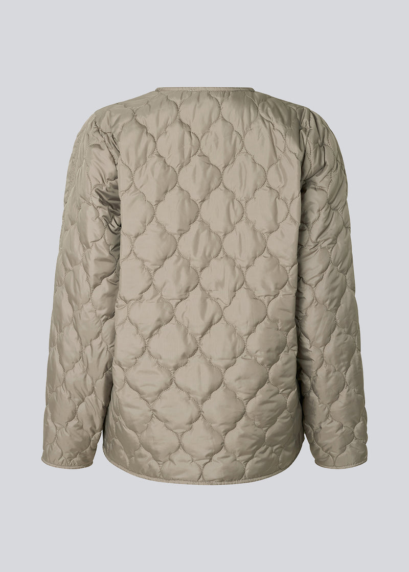 Lightly padded jacket in beige made from recycled nylon with quilted seams. CappelMD jacket has a relaxed shape detailed with a v-neck, long sleeves, and push buttons in front.