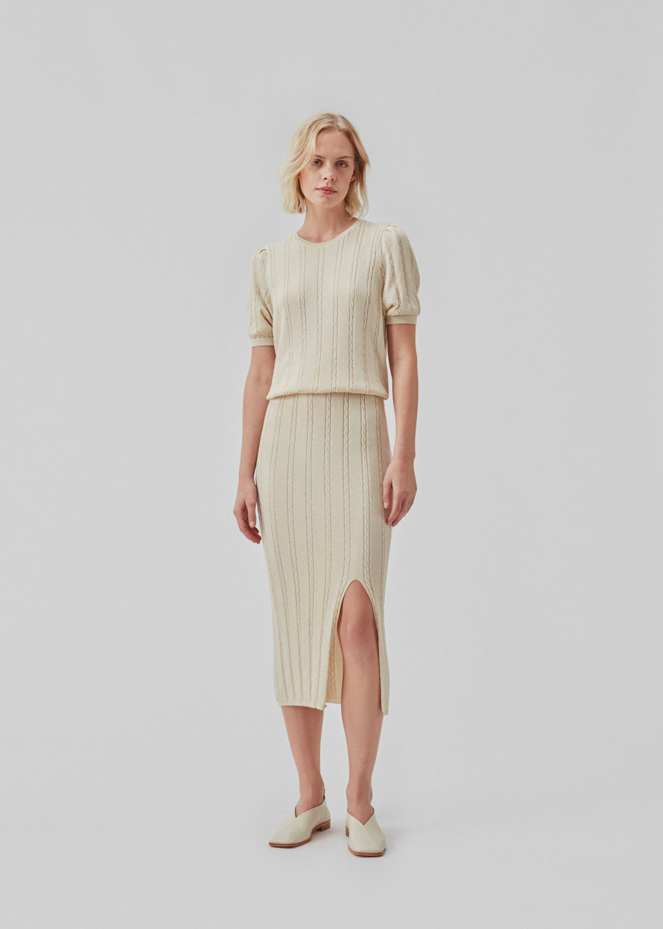 Short sleeved jumper in beige in cable knit with a round neck and puff sleeves. CarltonMD o-neck has a slim and stretchy shape. Shop the matching skirt: CarltonMD skirt. The model is 177 cm and wears a size S/36.