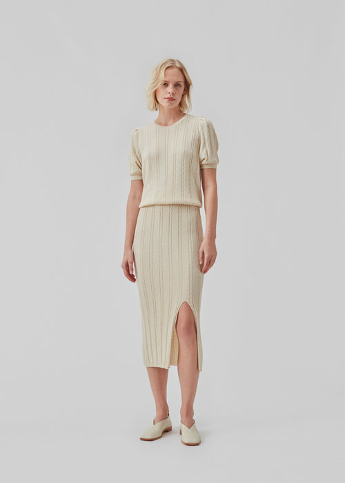 Cable knit skirt in midi length with a slit in front. CarltonMD skirt has a slim fit and a high waist with covered elasticated. The model is 177 cm and wears a size S/36.  Shop matching shirt: CarltonMD shirt.