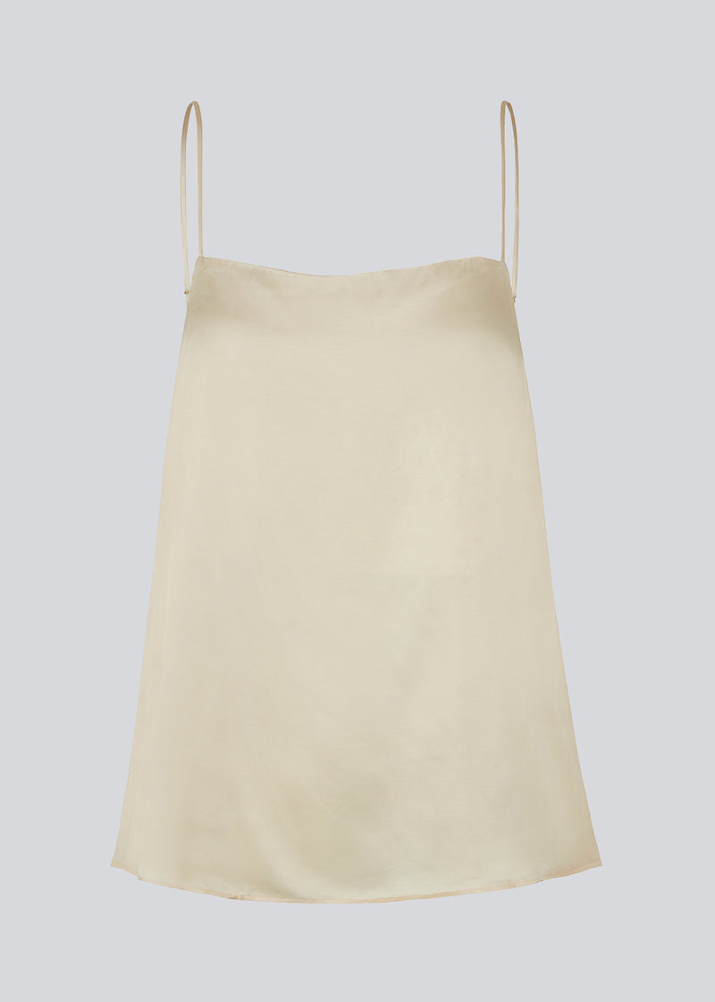 Satin top in beige with adjustable spaghetti straps and a clean expression. CarwynMD top has an A-shape and straight neckline. The model is 177 cm and wears a size S/36.