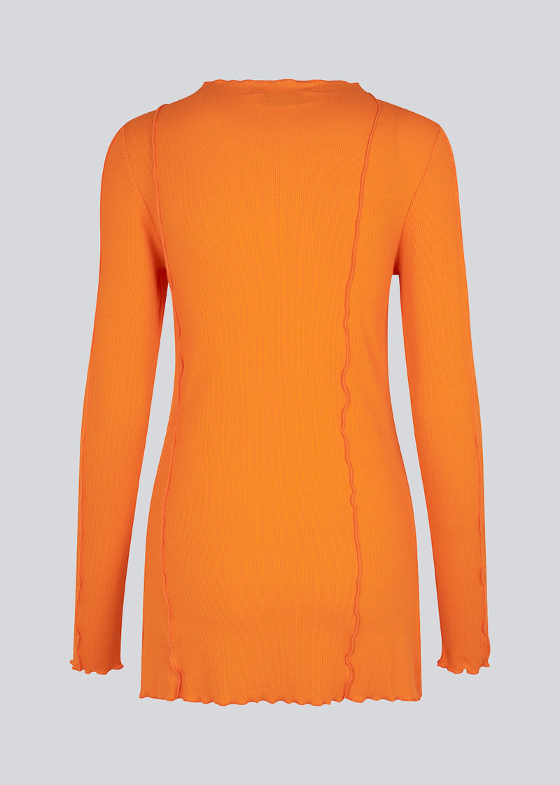 Blouse in orange with a high neck and visible seam details in an easy and soft material. CassieMD LS top is a slim-fit top with long sleeves and slits on both sides. The model is 177 cm and wears a size S/36.
