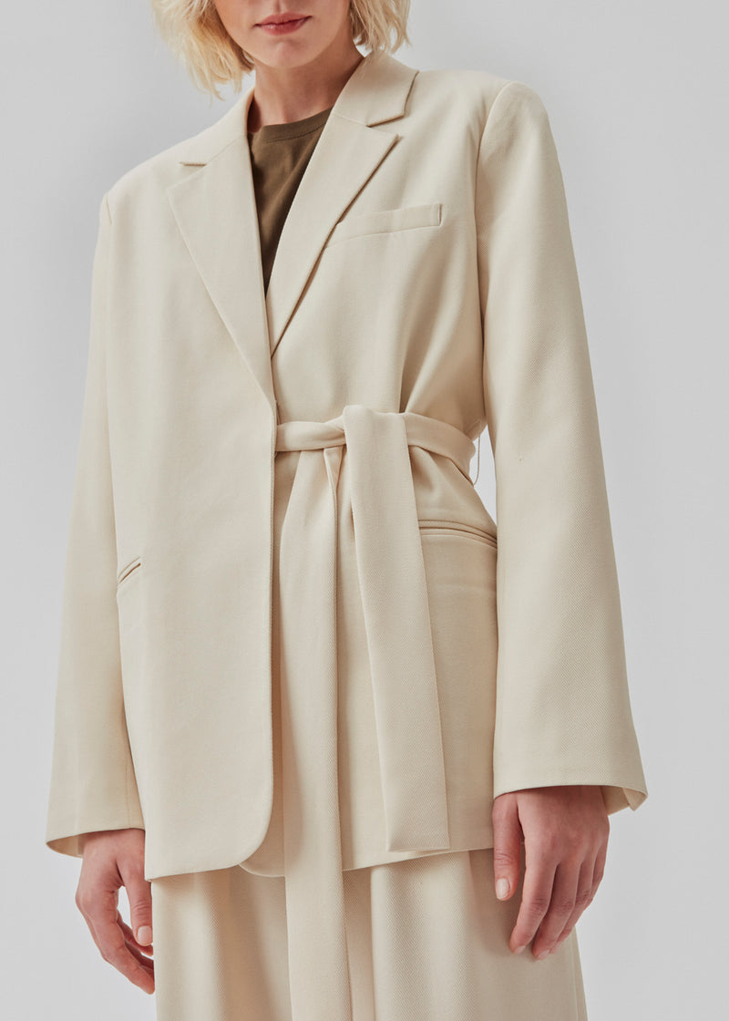 CayaMD blazer is designed for a relaxed fit with classic details with a twist from the tie-belt at the waist. Made from recycled materials. The model is 177 cm and wears a size S/36.  Style with the matching pants: CayaMD pants.
