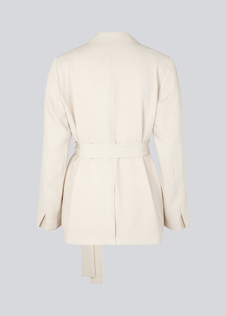 CayaMD blazer is designed for a relaxed fit with classic details with a twist from the tie-belt at the waist. Made from recycled materials. The model is 177 cm and wears a size S/36.  Style with the matching pants: CayaMD pants.