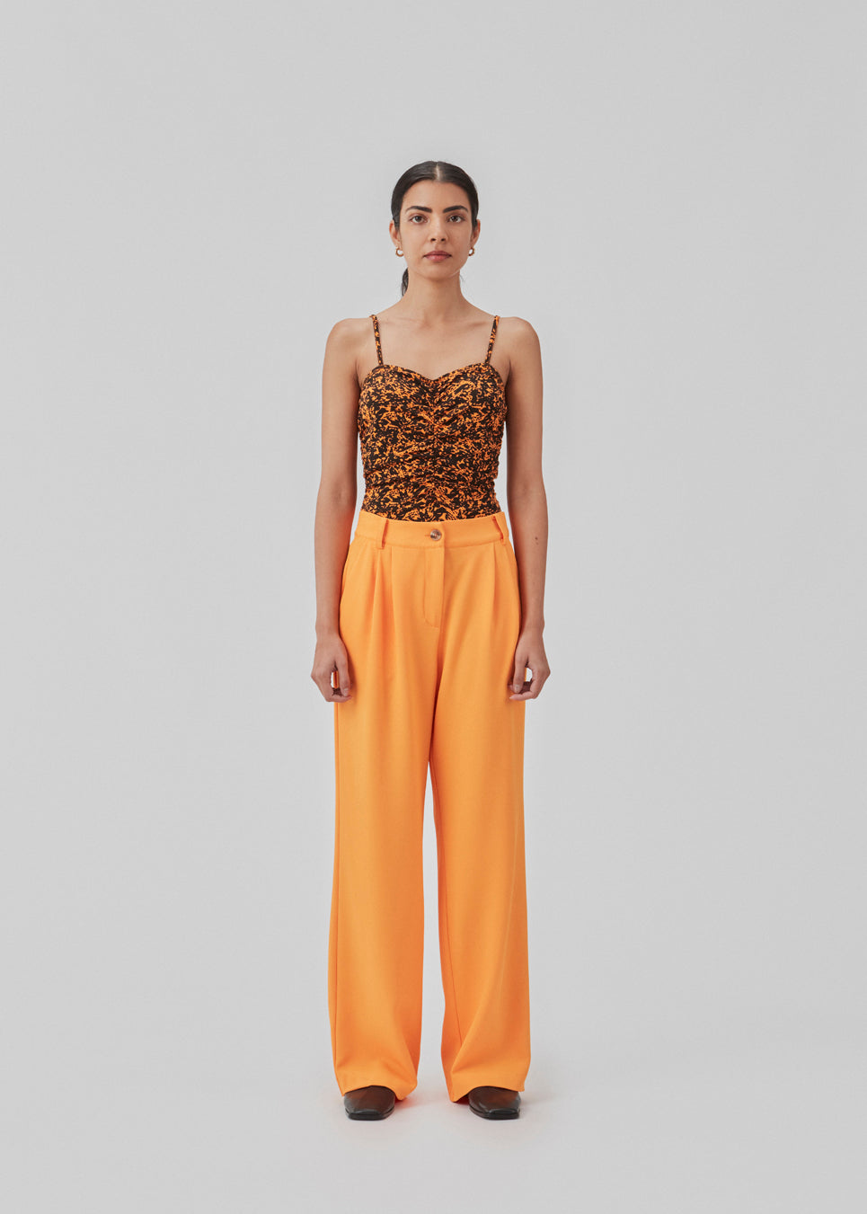 Loose pants in orange with wide legs made from recycled materials. Double pleating in front, zip fly and button closure. The model is 177 cm and wears a size S/36.  Style with the matching blazer: CayaMD blazer