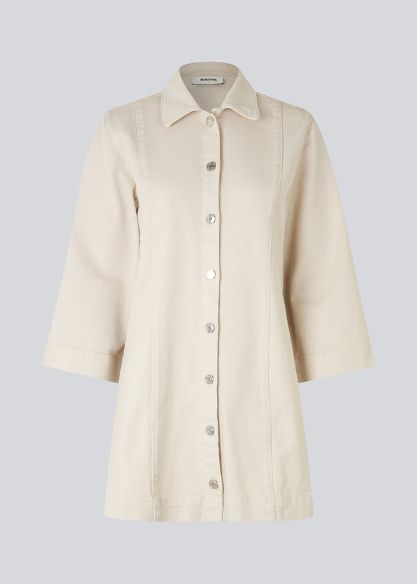 Short denim dress with a slight figure-hugging silhouette. ChikoMD dress has a collar and buttons down the front and 3/4 length wide sleeves. The model is 177 cm and wears a size S/36.  