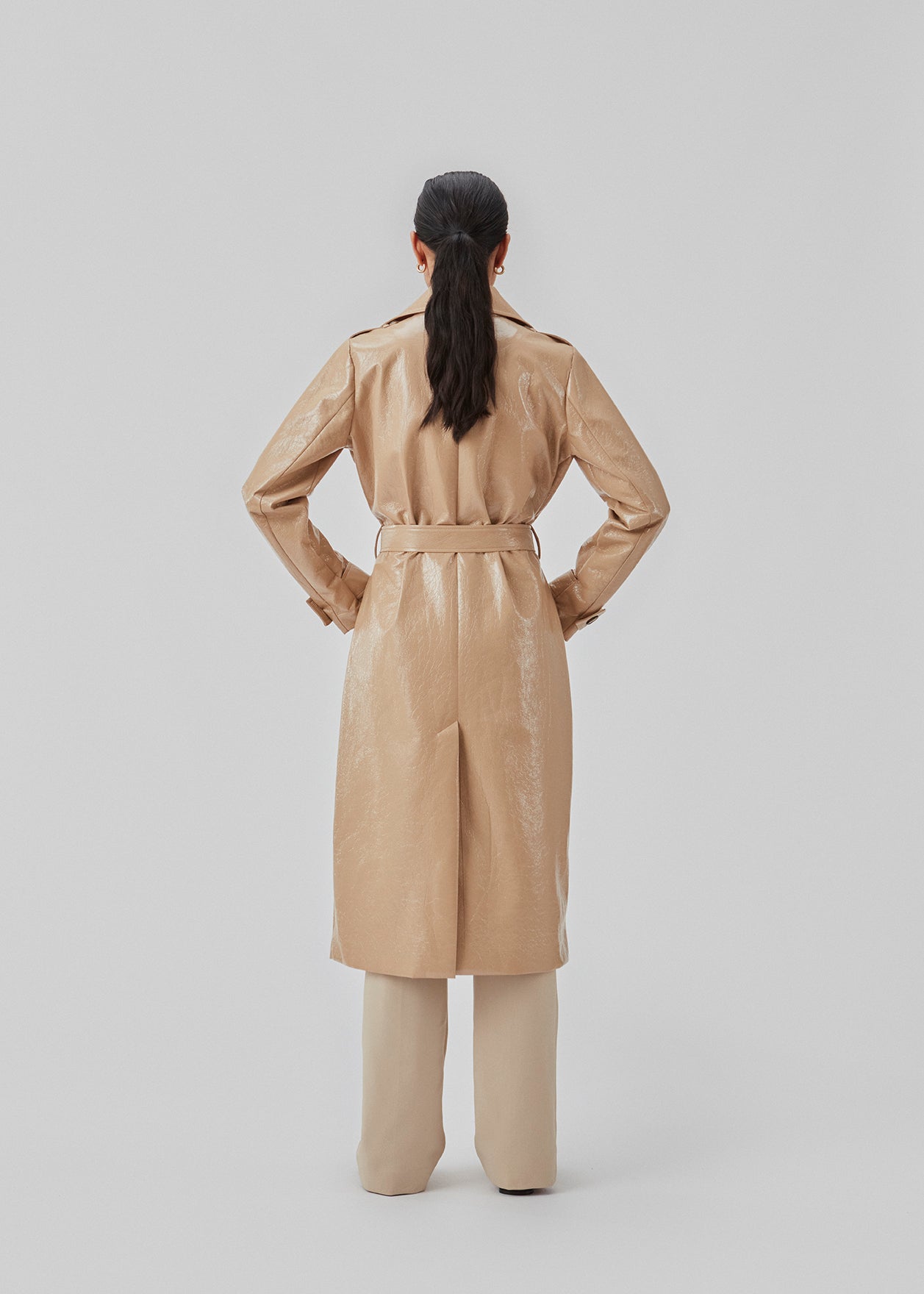 Coat in a shiny material. CollinsMD coat has a classic trenchcoat look with wide collar and lapel, button closure, and belt at the waist.