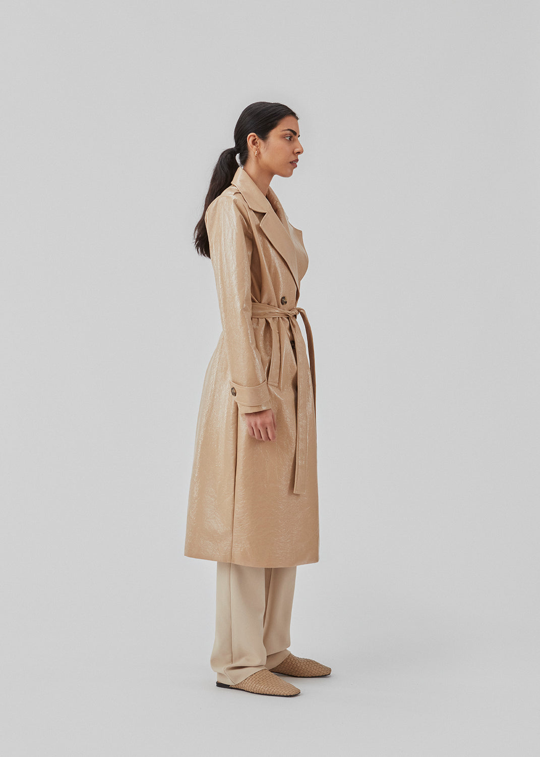 Coat in a shiny material. CollinsMD coat has a classic trenchcoat look with wide collar and lapel, button closure, and belt at the waist.