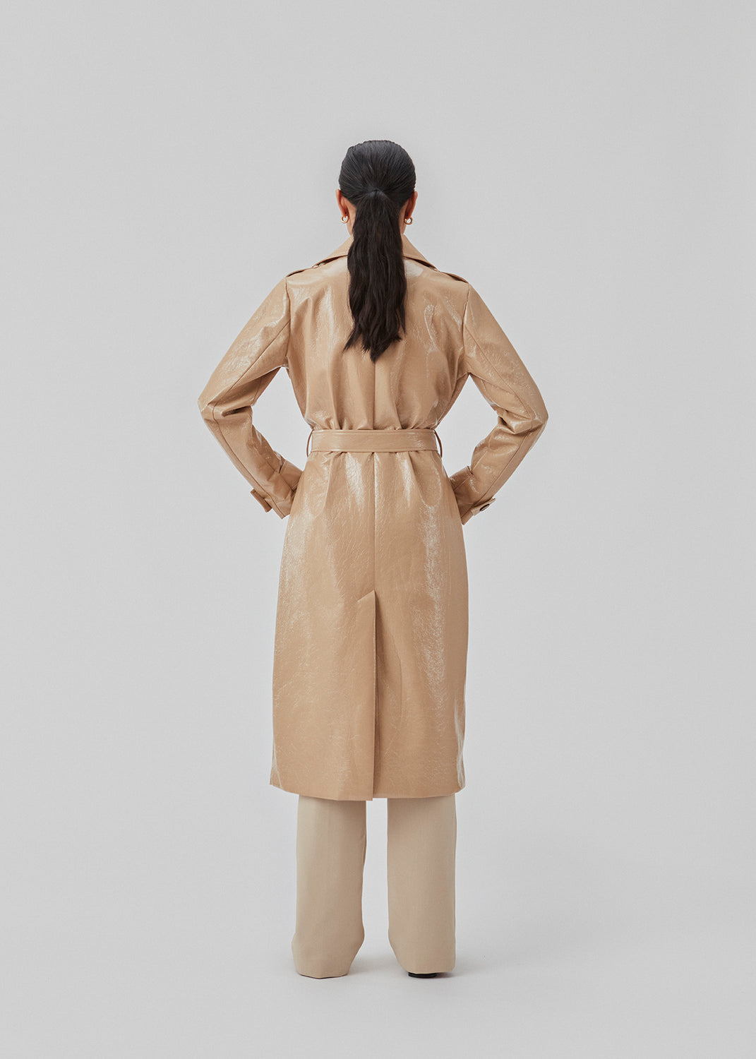 Coat in a shiny material. CollinsMD coat has a classic trenchcoat look with wide collar and lapel, button closure, and belt at the waist.
