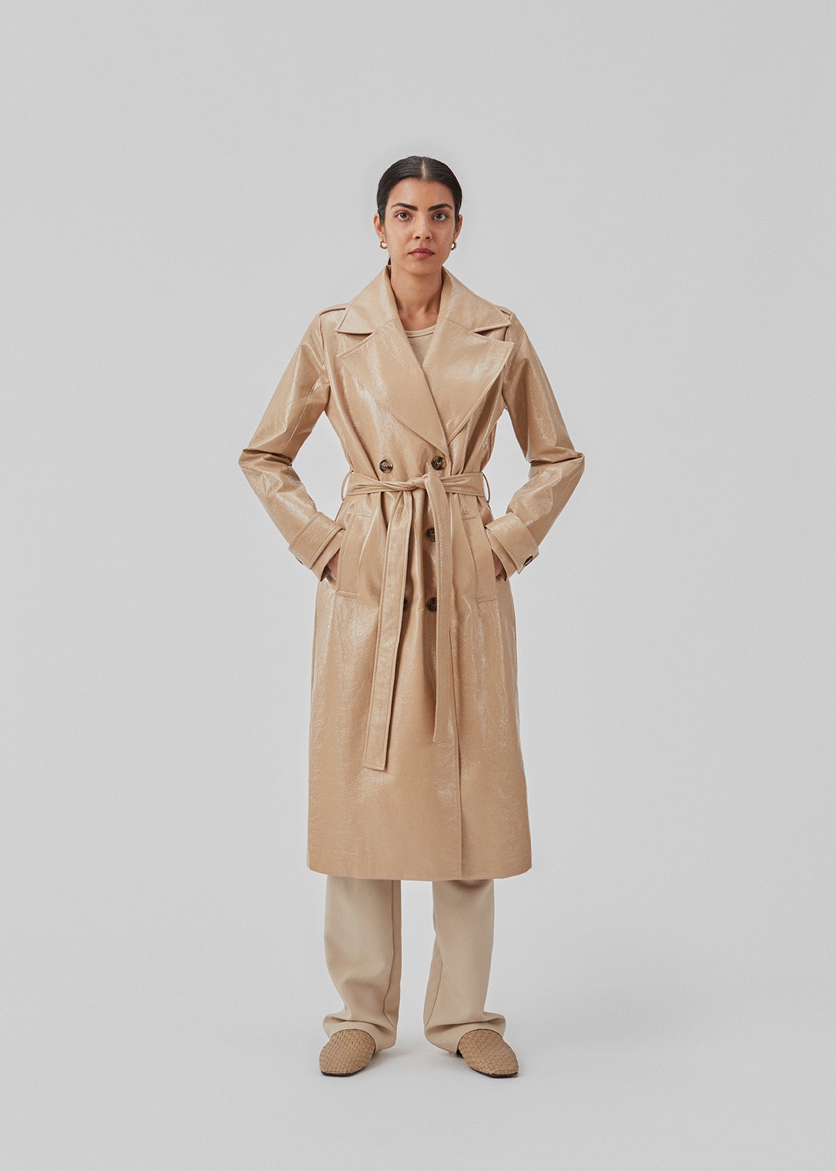 Coat in a shiny material. CollinsMD coat has a classic trenchcoat look with wide collar and lapel, button closure, and belt at the waist.