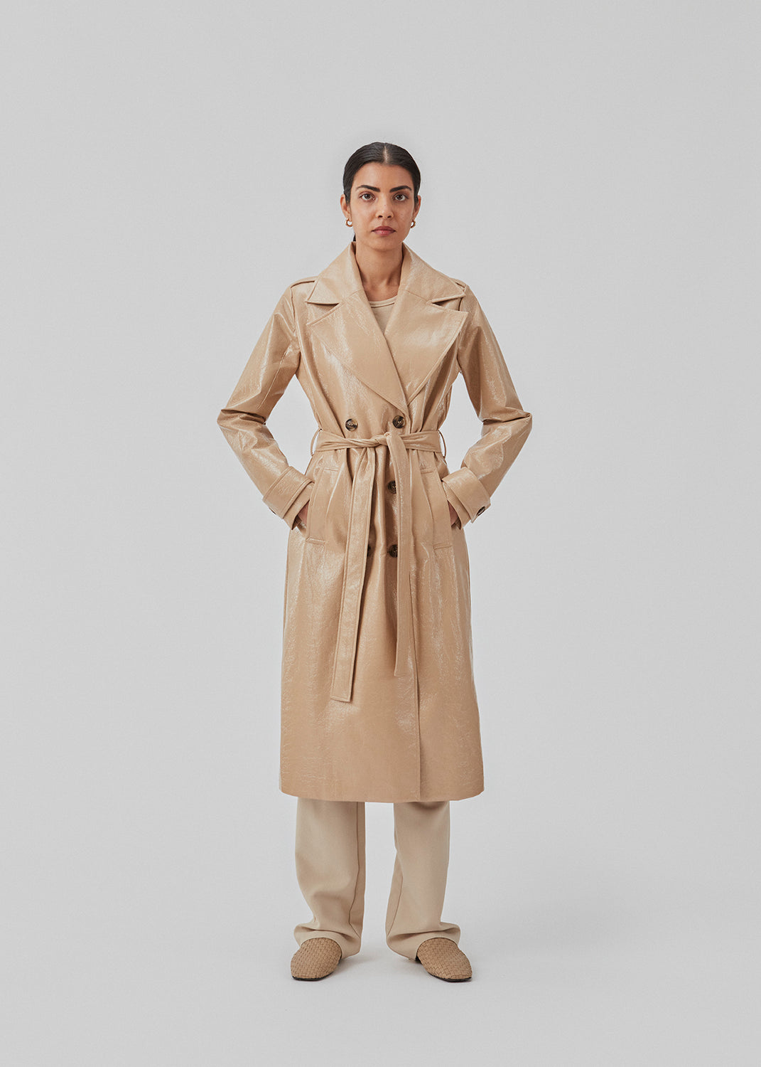 Coat in a shiny material. CollinsMD coat has a classic trenchcoat look with wide collar and lapel, button closure, and belt at the waist.