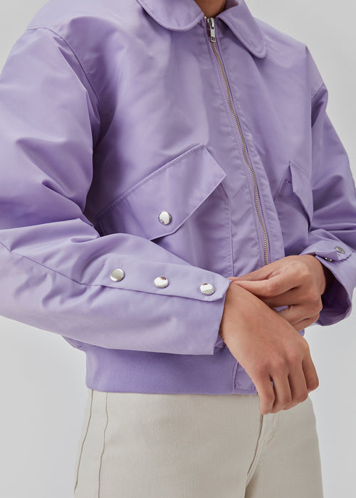 Short, padded bomber jacket in purple. ColtonMD jacket is designed with a collar, zipper in front, and pockets with push buttons. Ribbing at the hem.