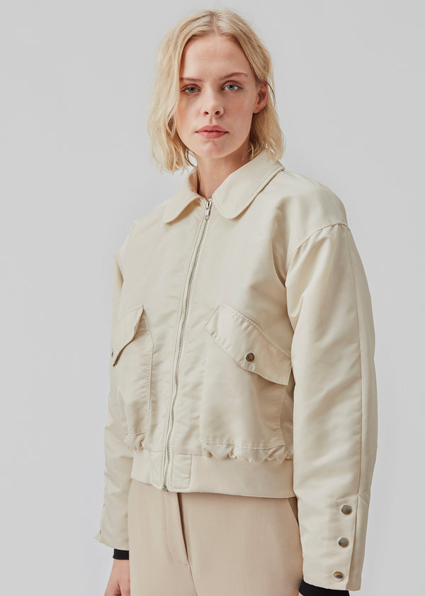 Short, padded bomber jacket in beige. ColtonMD jacket is designed with a collar, zipper in front, and pockets with push buttons. Ribbing at the hem.
