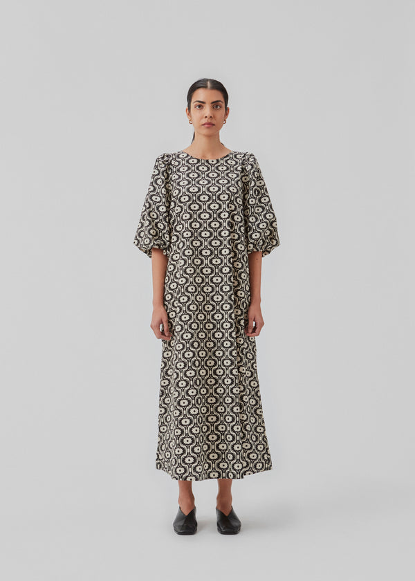Long dress with a wide skirt and voluminous puff sleeves. CoraMD print dress has a round neck with a cut out and bow in the back. Made from organic cotton.  The model is 174 cm and wears a size S/36.