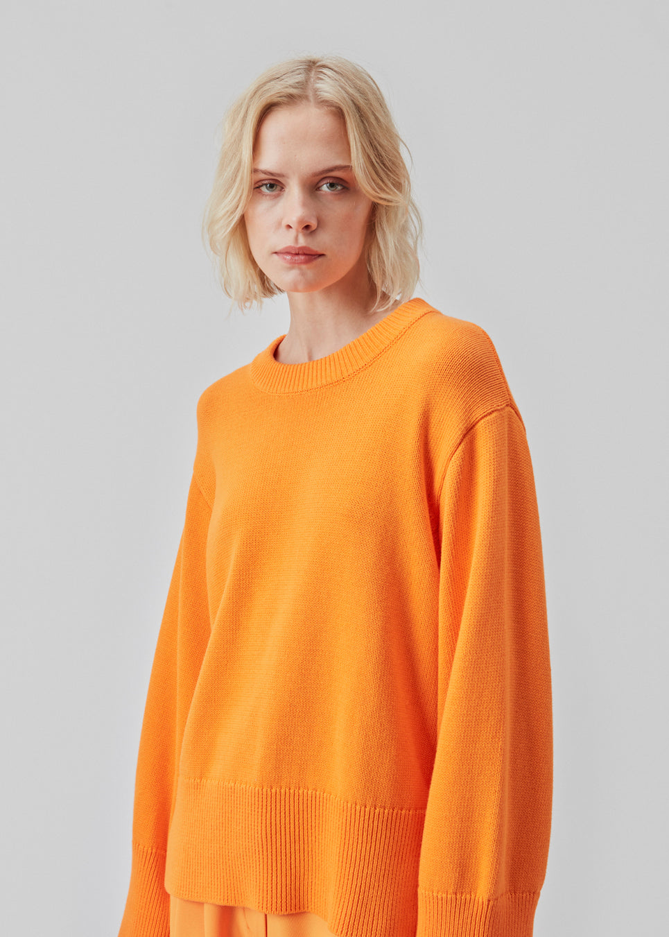 Fine-knitted oversize jumper orange knitted from cotton. CorbinMD o-neck has ribbed round neckline, long wide sleeves, and wide ribbing at cuffs and hem.
