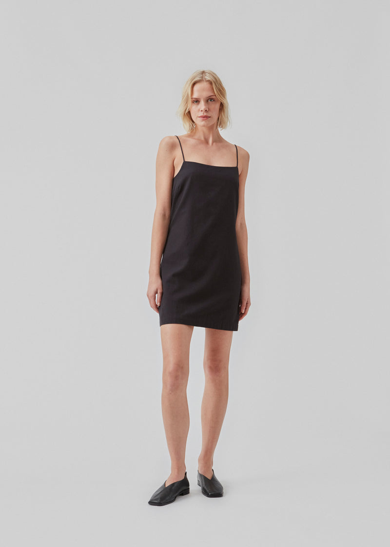 Short dress in black with a clean look in woven cotton. CydneyMD dress is slightly tailored, has adjustable straps, and a hidden zipper on one side. The model is 174 cm and wears a size S/36.