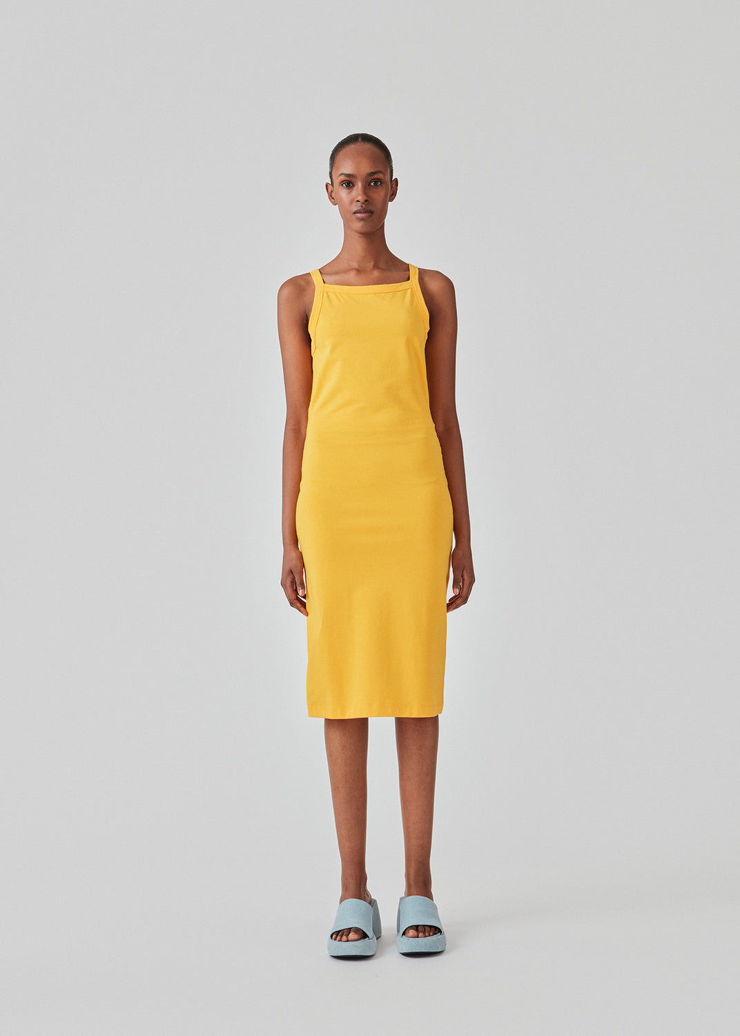 Tight fitted basic yellow dress in organic cotton jersey. DaeMD dress is sleeveless with a high and straight neckline. The dress cuts below the knees. The model is 177 cm and wears a size S/36.