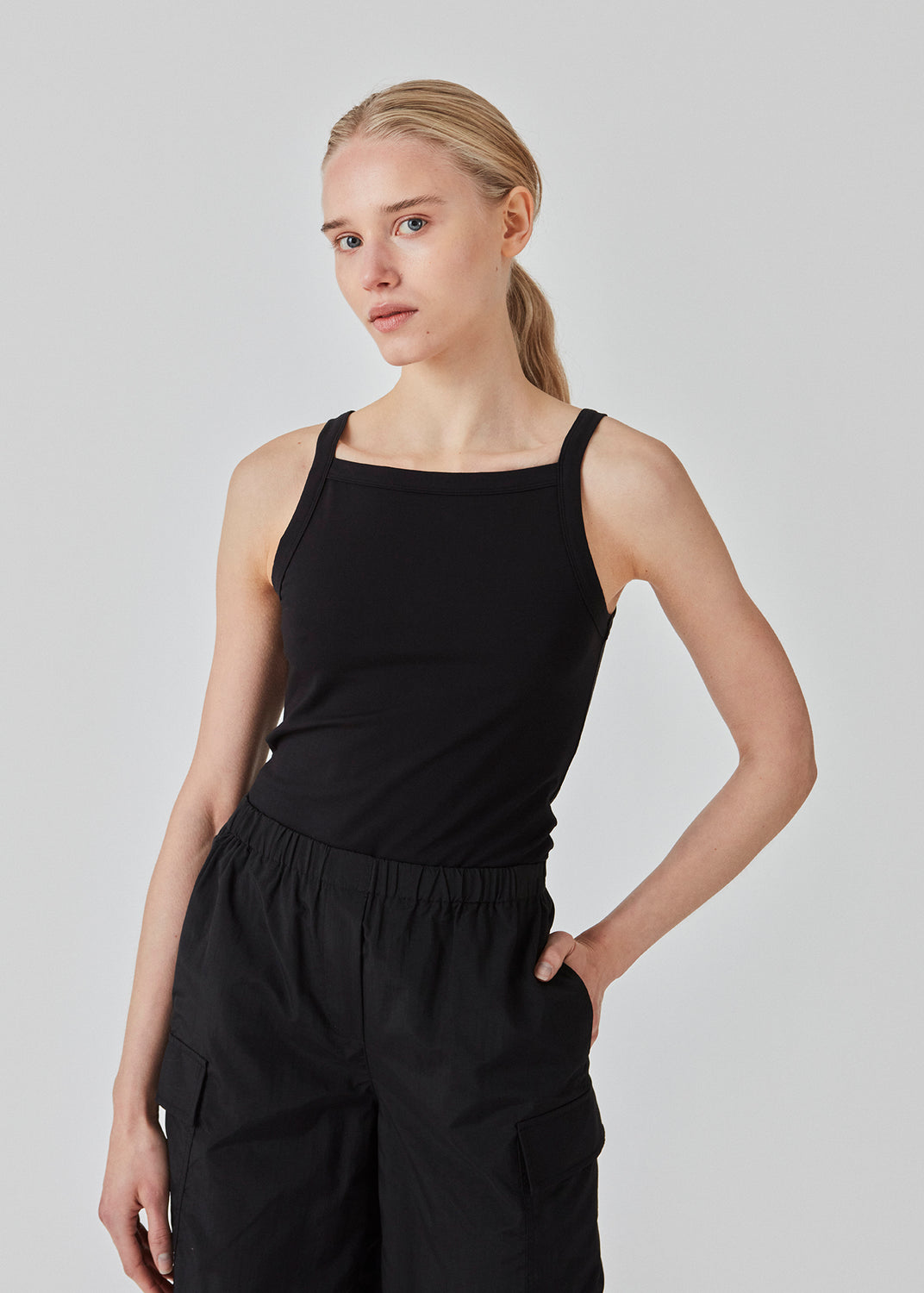 Tight fit basic black top with a high and straight neckline. DaeMD top is made from a rib-knitted organic cotton. The model is 177 cm and wears a size S/36.