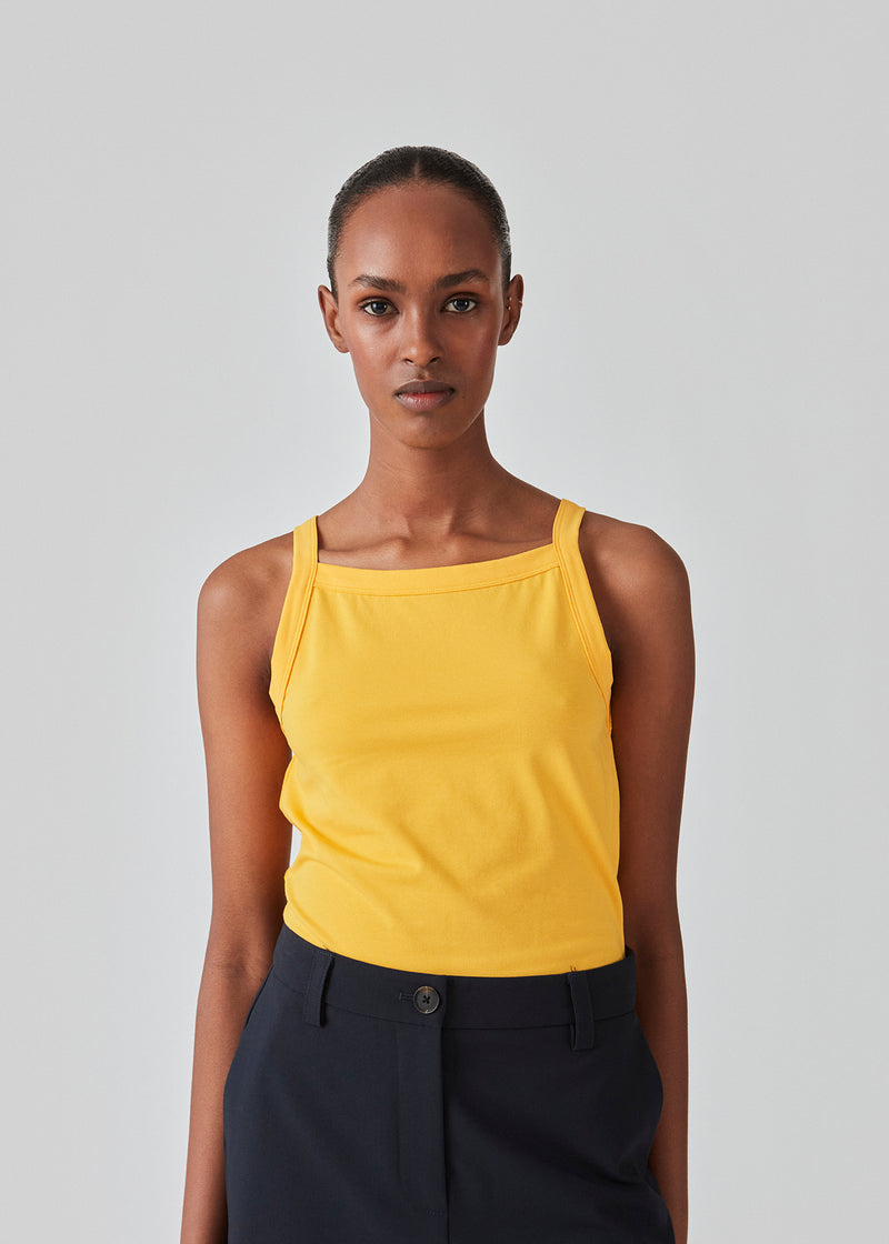Tight fit basic yellow top with a high and straight neckline. DaeMD top is made from a rib-knitted organic cotton. The model is 177 cm and wears a size S/36.