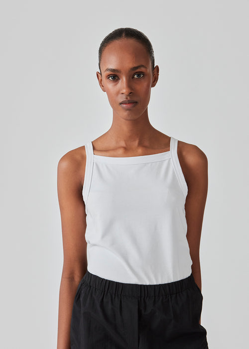 Tight fit basic white top with a high and straight neckline. DaeMD top is made from a rib-knitted organic cotton. The model is 177 cm and wears a size S/36.