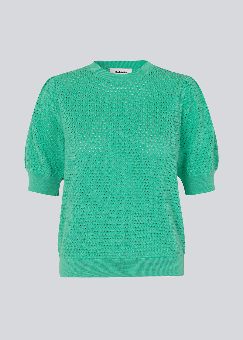 DariaMD o-neck is an open-knitted jumper in green with short puff sleeves and a round neck. Ribbed trimmings at the bottom, neckline, and cuffs. The model is 177 cm and wears a size S/36.