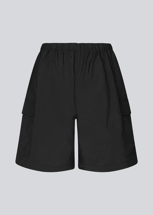 Cargo shorts in black in nylon with wide legs. DilaraMD shorts have an elasticated waistband and two large patch pockets on the sides. The model is 177 cm and wears a size S/36.