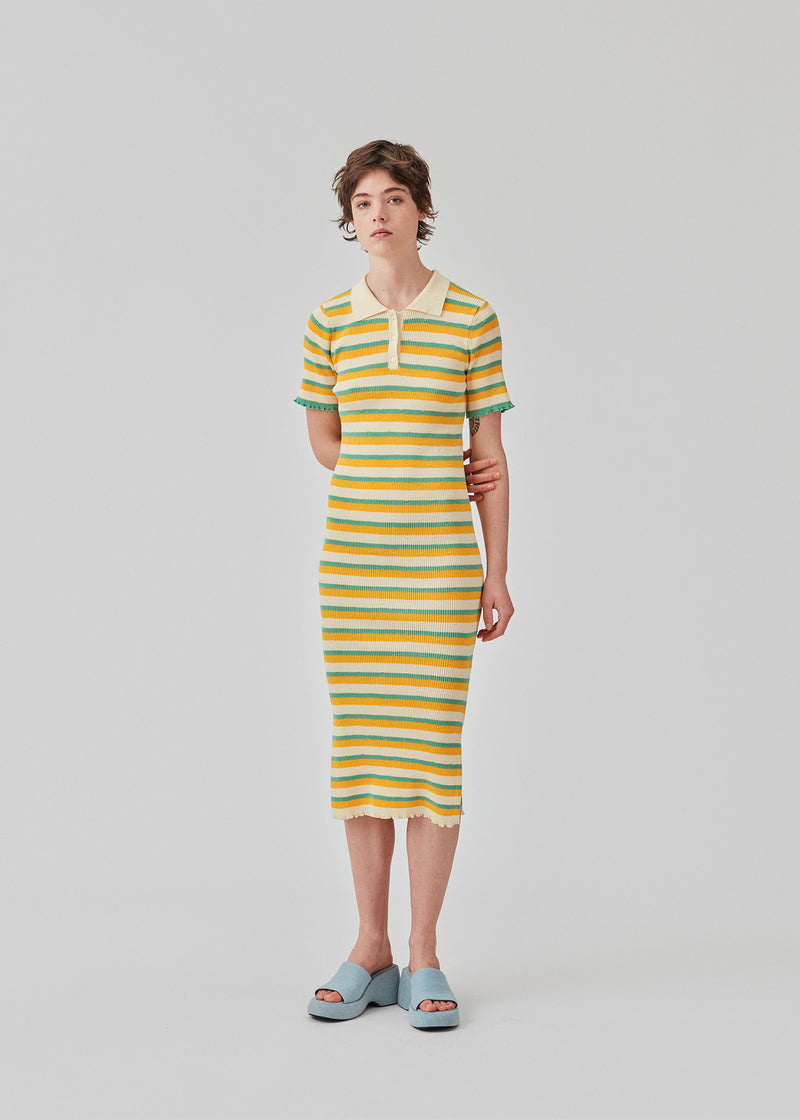  Tight fit long dress in a stretchy quality with stripes. DorisMD dress features a polo collar with buttons, short sleeves, and lettuce hems. The model is 177 cm and wears a size S/36.