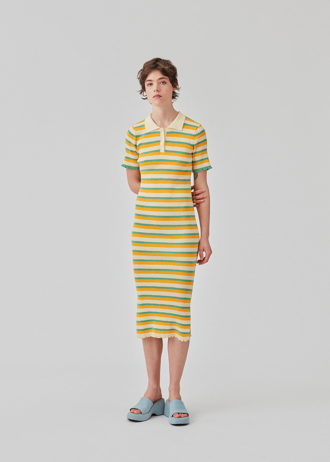  Tight fit long dress in a stretchy quality with stripes. DorisMD dress features a polo collar with buttons, short sleeves, and lettuce hems. The model is 177 cm and wears a size S/36.