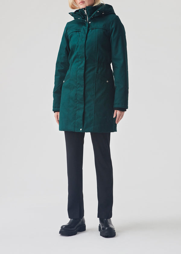 Green jacket. Frida has a hoodie, is knee-length and has an invisible button/zipper closure. The jacket has a tight fit, which gives a feminine look. The padding is M3 Thinsulate, which is recognized for its high insulation ability and is, therefore, the perfect choice.