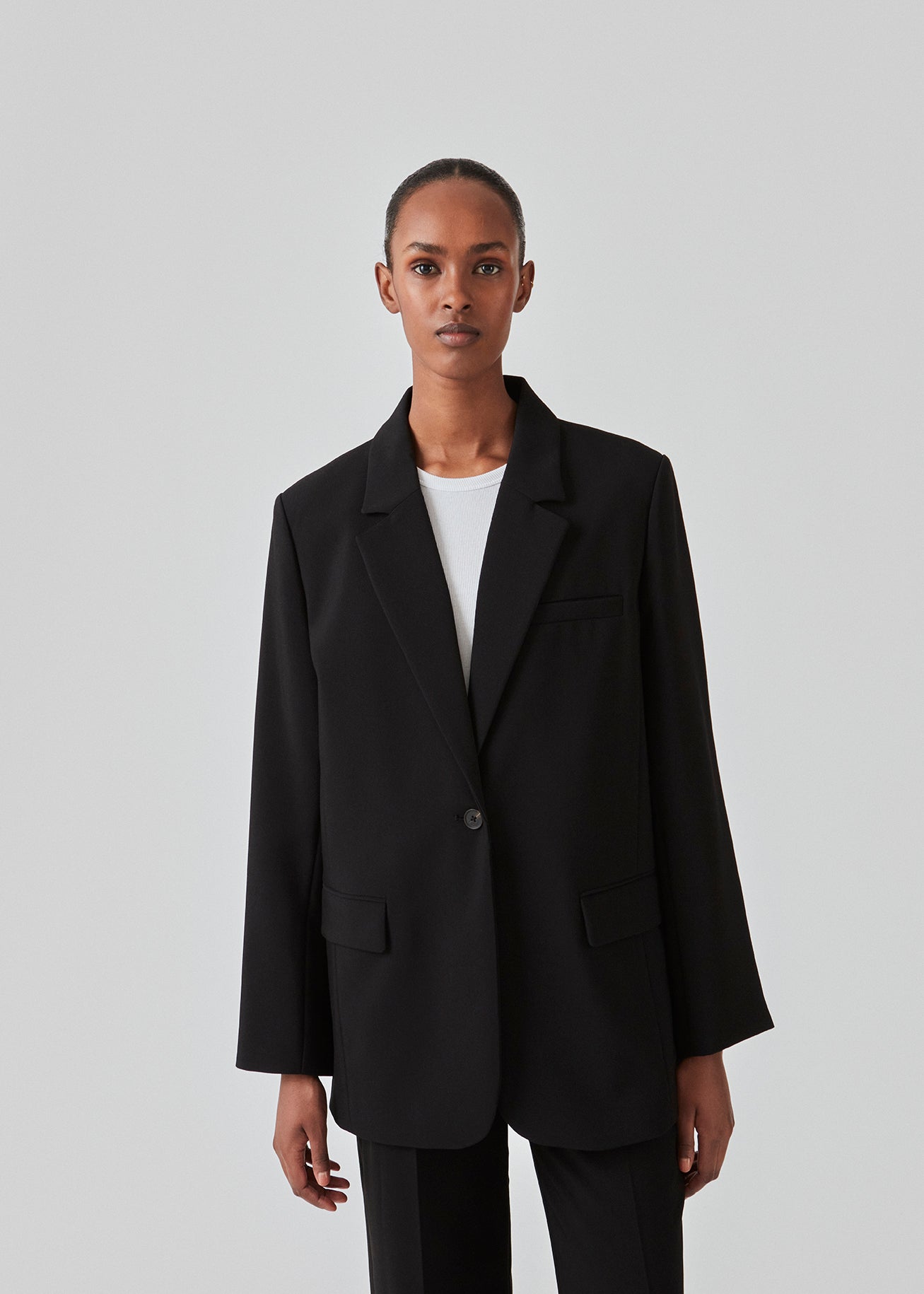 Gale blazer in Black has a classic and elegant design, fulfilled by the beautiful revers collar and a long fit. The blazer has a button closure at the front and a chest pocket at the left side. Buy Gale Pants, Gale straight pants, GaleMD skirt or GaleMD shorts in the same color that fits the Blazer.  The model is 177 cm and wears a size S/36.  This blazer has a spacious fit. We recommend sizing down.