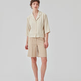 GaleMD shorts in beige have a classic design. The shorts cuts at knee-length, and have wide legs with creases for an elegant look. The model is 173 cm and wears a size S/36.  Buy Gale blazer in the same color that fits the shorts.