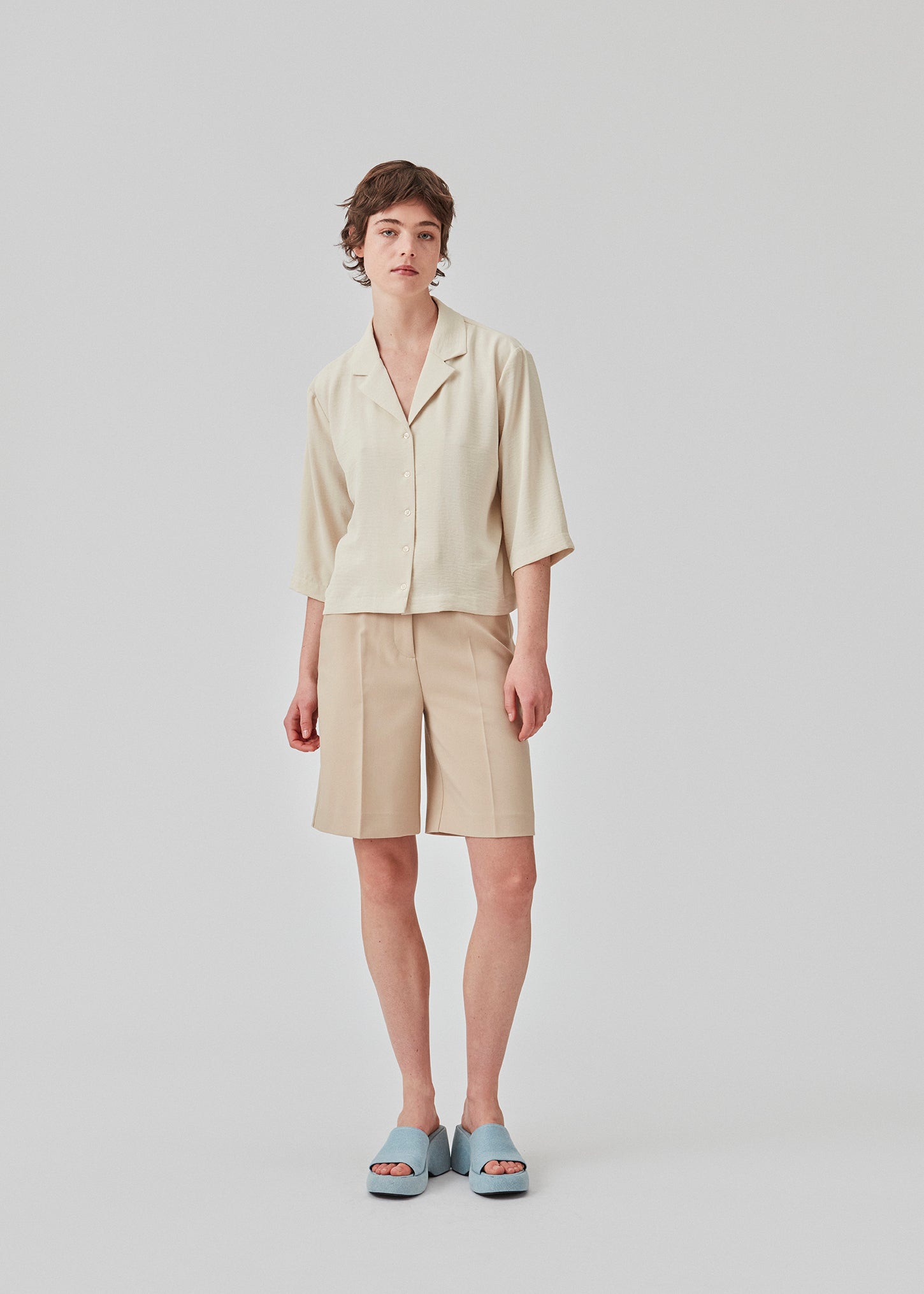 GaleMD shorts in beige have a classic design. The shorts cuts at knee-length, and have wide legs with creases for an elegant look. The model is 173 cm and wears a size S/36.  Buy Gale blazer in the same color that fits the shorts.