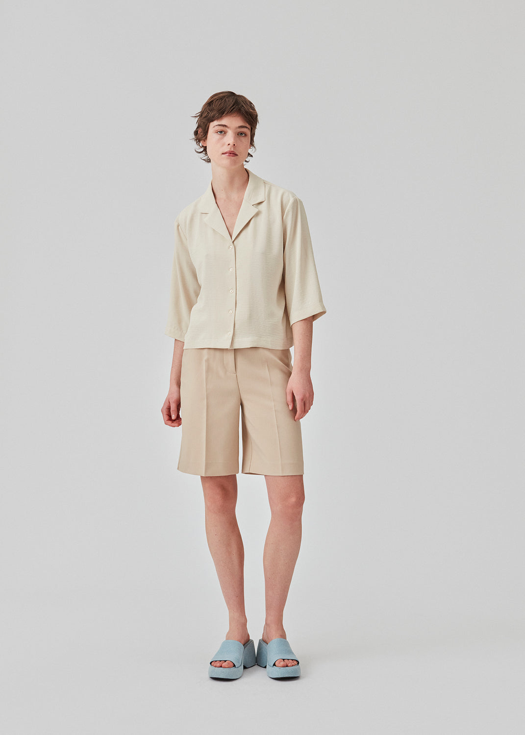 GaleMD shorts in beige have a classic design. The shorts cuts at knee-length, and have wide legs with creases for an elegant look. The model is 173 cm and wears a size S/36.  Buy Gale blazer in the same color that fits the shorts.