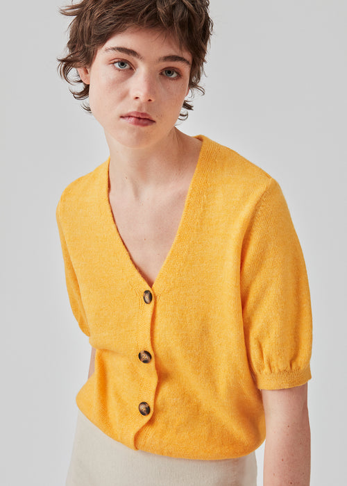 Trendy cardigan in yellow with short puffy sleeves and button closure at the front. Irene cardigan comes in a soft material perfect for the early spring days. The model is 174 cm and wears a size S/36
