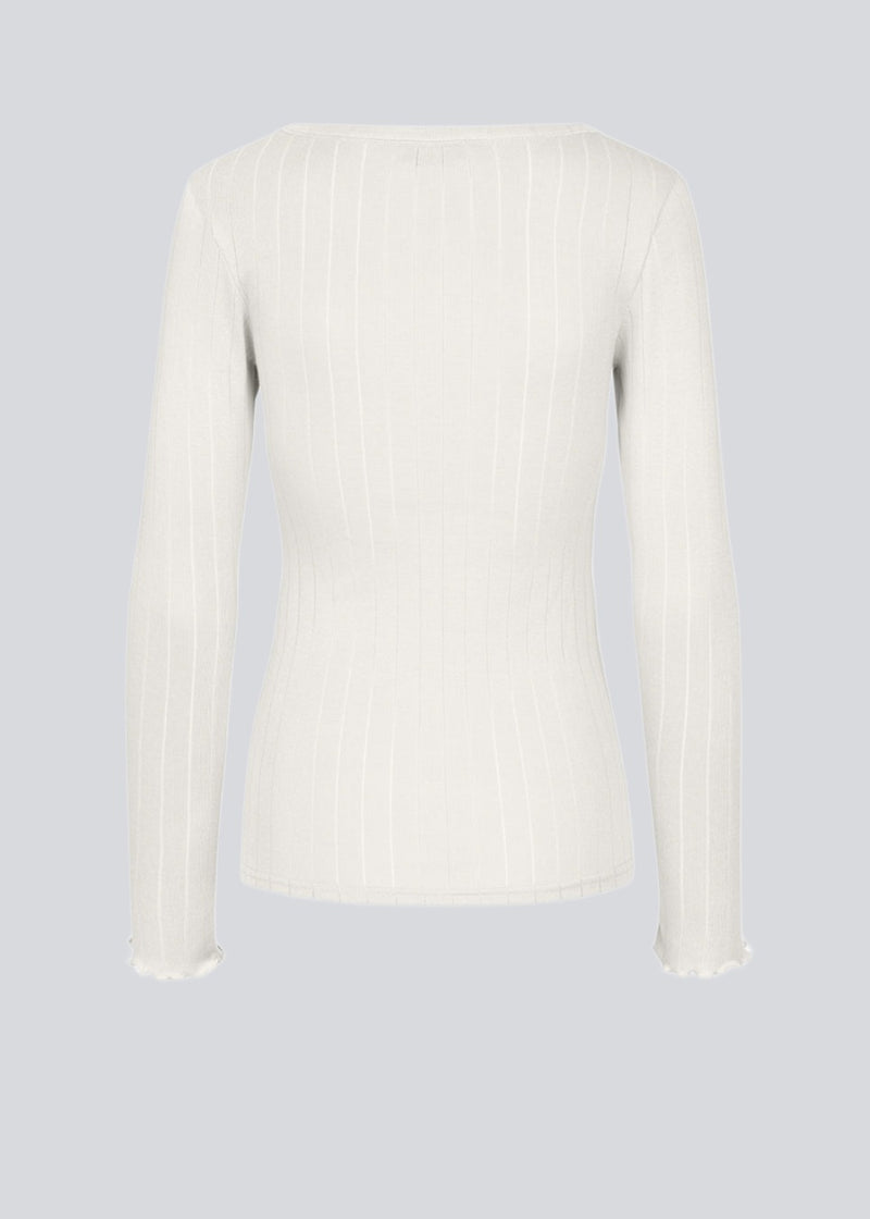 Tight fitted longsleeved t-shirt with a feminine lettuce trim on the sleeves. Issy LS t-shirt in color Off White is made from a soft jersey quality with a decorative drop needle pattern.