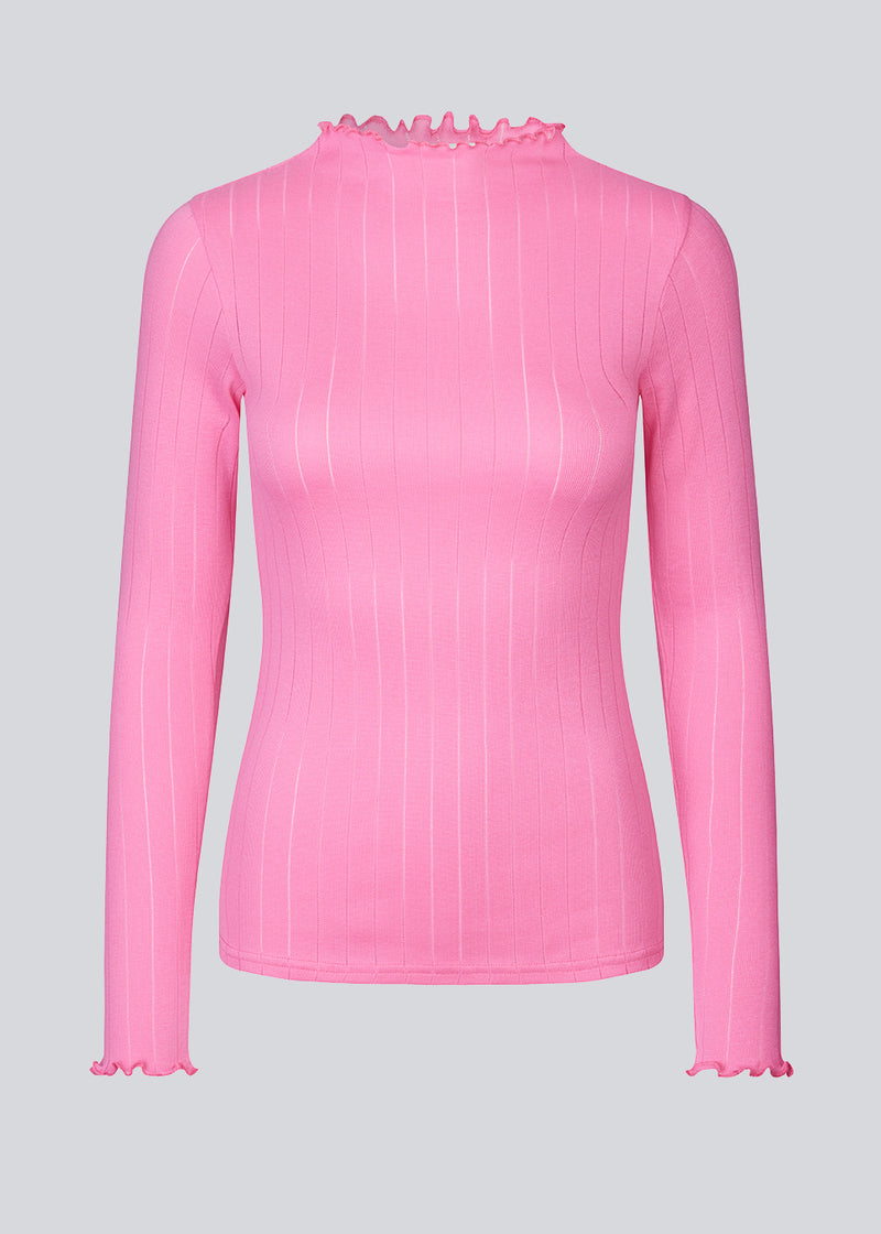 Tight fitted t-shirt in pink with a medium high neck. Issy t-neck has feminine lettuce hem on neck and sleeves. The quality is a soft jersey with a feminine pointelle pattern.