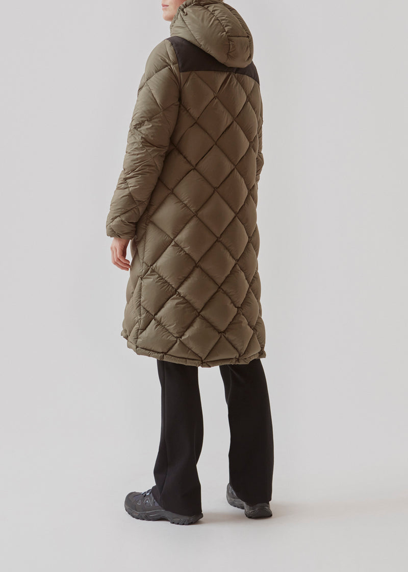 Smart down coat in a diamond quilt in dark green. The coat has a hood with adjustable strings and two zipped pockets. Kyra coat has a down filling, which gives an outstanding insulation from the cold - even on the coldest days. Keep you warm down to -15 degrees. It’s water repellant, wind resistant