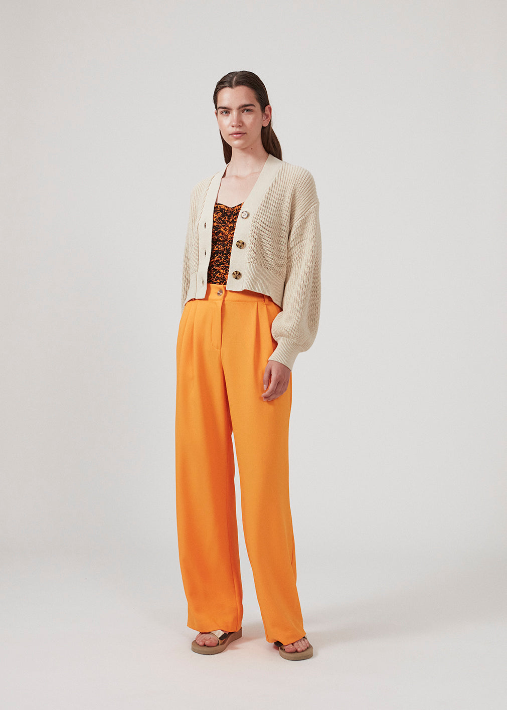 Loose pants in orange with wide legs made from recycled materials. Double pleating in front, zip fly and button closure. The model is 177 cm and wears a size S/36.  Style with the matching blazer: CayaMD blazer