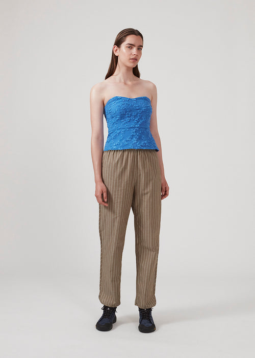 Crop top in blue without sleeves with a heart-shaped neckline and a slight peplum-effect. AtiraMD crop top has a structured floral pattern.  The model is 177 cm and wears a size S/36.