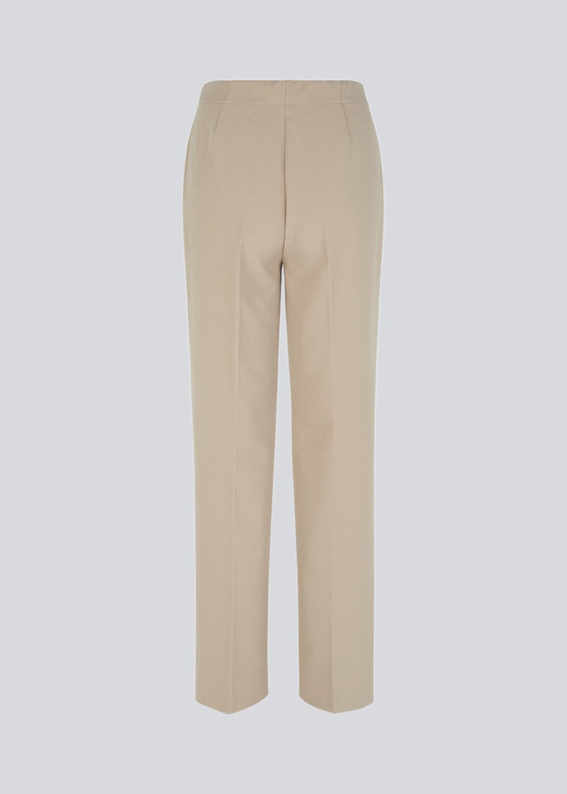 Classic pants with pressfolds and straight legs. Nelli pants are closes by an hidden zipper at the side with an elastic waistband for a more comfortable fit. The model is 173 cm and wears a size S/36