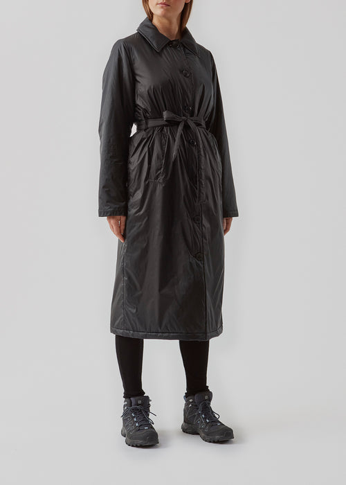 Sporty coat with collar, buttons and waist belt. Oma jacket is a cool coat in nylon in voluminous but feminine silhouette. The light padding of the coat is 100% recycled polyester. The model is 173 cm and wears a size S/36