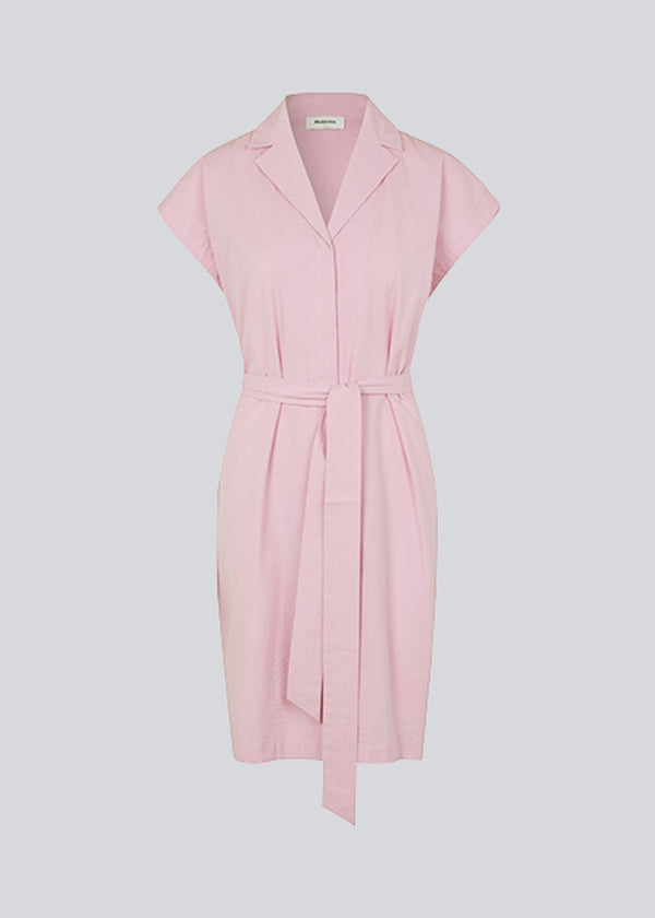 Panne dress is a cotton dress in the color dusty sorbet with a beautiful silhouette. The dress features a nice collar, tie band, and a sleeveless design with wide shoulders. The model is 173 cm and wears a size S/36.