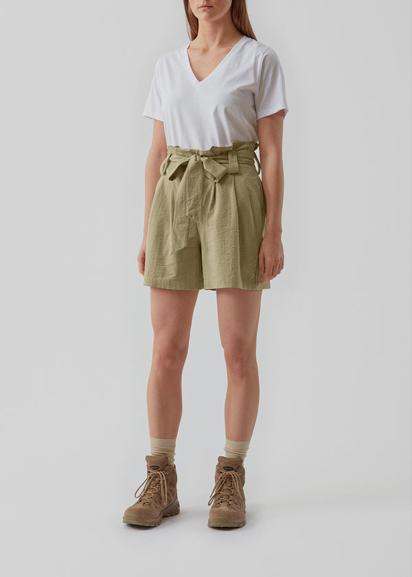 Panne shorts in the color Elm are made from a structured cotton quality. These shorts have a casual, high-waisted silhouette detailed with a belt at the waist. The model is 173 cm and wears a size S/36. 